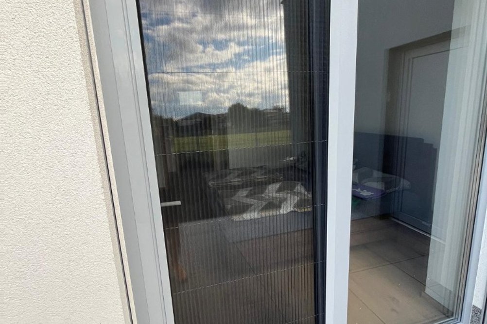 Šedé balkonové dveře se sítí proti hmyzu