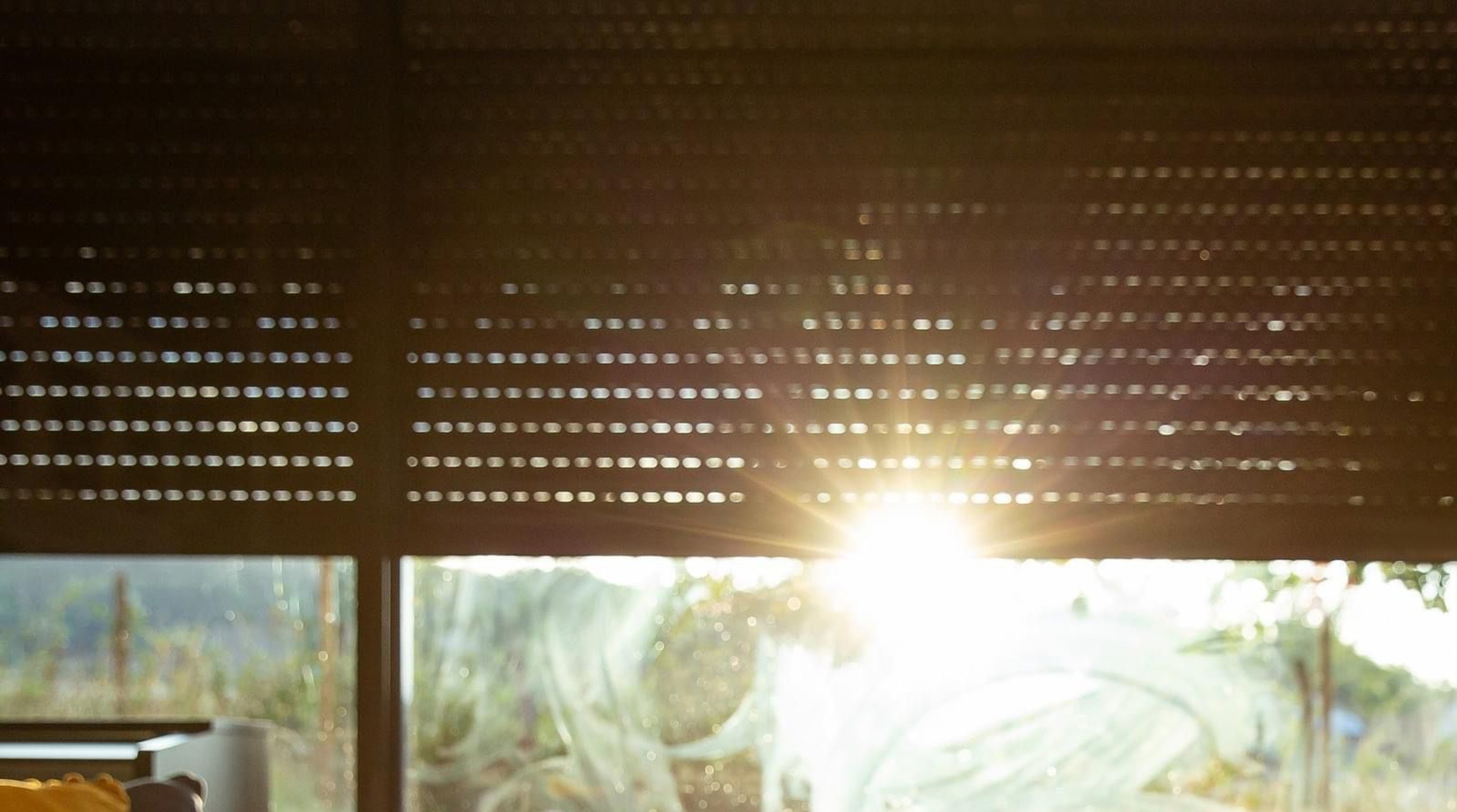 Pohled ven z okna s polozateženými solárními roletami