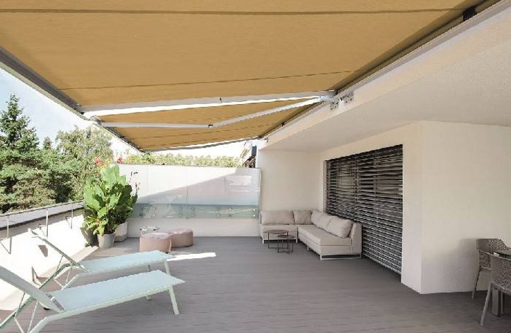 Výsuvná markýza od Hezký stín vytváří na prostorné střešní terase příjemný stín pro relax na lehátkách i pohodlné sezení v rohové sedačce.