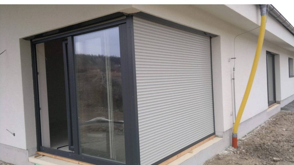 Skrytá předokenní roleta u posuvných dveří – čistý vzhled fasády.