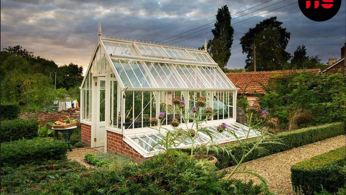 Viktoriánský skleník Aiton v anglickém stylu s cihlovou podezdívkou uprostřed upravené zahrady – luxusní zahradní skleník pro pěstování rostlin po celý rok.